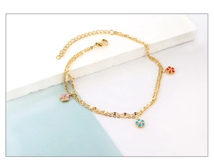 Detail of double-layer gold anklet with colorful enamel flowers on blue background