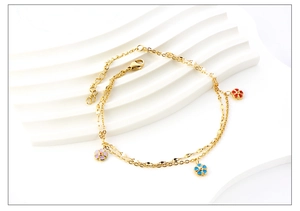 Detail of double-layer gold anklet featuring three colorful enamel flower pendants