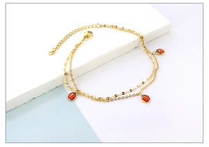 Detail of gold-layered anklet featuring red ladybug charms and lobster clasp closure