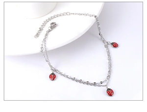 Close-up of double-layer stainless steel anklet with three red ladybug charms and extender