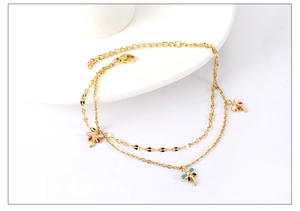 Detail view of a gold-plated double-layer anklet featuring colorful enamel dragonfly charms