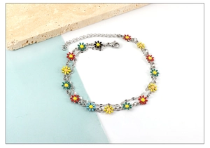 Detail view of multi-color enamel daisy charms on an adjustable silver chain anklet