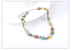 Detailed macro view of colorful daisy enamel charms on silver stainless steel anklet chain