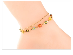 Detail of double-layer gold anklet featuring multi-colored enamel daisy flower charms