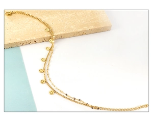 Detailed macro view of golden double-layered ankle bracelet with smiley face charms