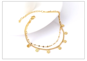 Detailed view of gold double-layer daisy smiley face anklet on white ceramic plate