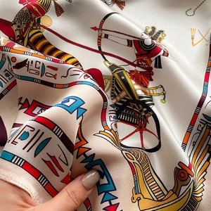 Detailed view of silk square scarf featuring ancient Egyptian patterns and warriors