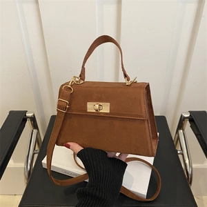 Petit sac bandoulière en daim marron caramel avec fermoir doré porté à la main pour le quotidien