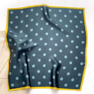 Green silk scarf with blue polka dots and yellow border paired with a beige blazer