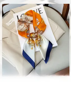 Detail of a square silk scarf with baroque floral patterns and chic orange color block