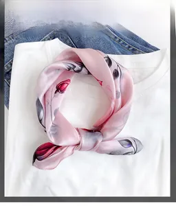 Detail of pink silk scarf with red rose pattern tied in a bow on a white T-shirt
