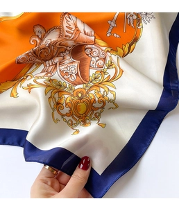 Detailed macro view of baroque silk scarf featuring golden crest patterns and rolled edges