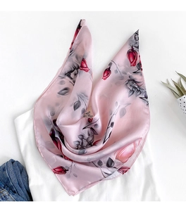Detail of pink silk scarf featuring realistic red rose print on smooth satin fabric