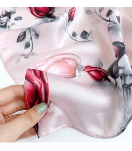 Detail of pink silk scarf showing red rose patterns and premium satin texture finishes