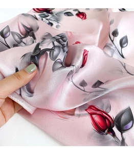 Macro shot of pink silk scarf showing smooth texture and red rose floral print details