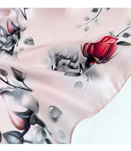 Detailed view of light pink silk scarf with red rose pattern and glossy satin finish