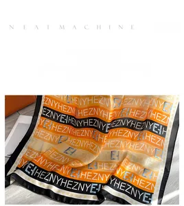Détail d'un foulard en soie de luxe avec rayures orange et noires et motif de lettres