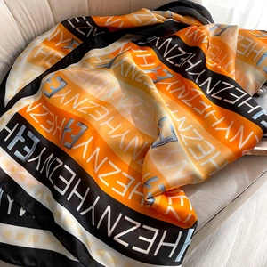 Gros plan détaillé d'un foulard en soie orange et noir imprimé sur velours beige