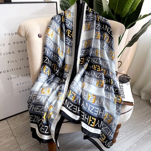 Écharpe chic en satin avec imprimé lettre doré sur fond noir et blanc sur canapé