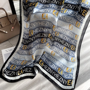 Écharpe en soie à motif de lettres drapée élégamment à côté d'un sac à main de luxe
