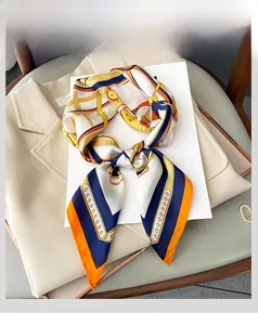 Détail d'un carré de soie avec motifs équestres et chaînes sur un blazer chic