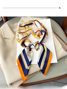 Détail d'un élégant carré de soie aux motifs de chaînes sur un blazer beige chic