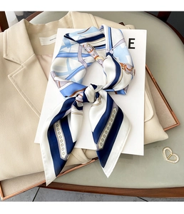Vue détaillée d'un foulard en soie à motifs bleu et blanc porté sur un blazer beige