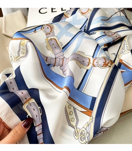 Détail d'un foulard en soie avec motifs équestres bleus sur une texture satinée