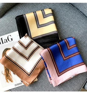 Close-up of silk neck scarves with geometric L-line patterns on a textured background