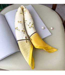 Detailed shot of floral silk scarf with yellow flowers and pearl brooch on a magazine