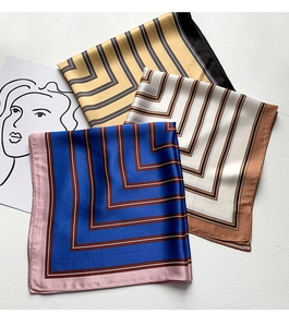 Detail view of geometric stripe pattern on smooth silk scarves in three assorted colors