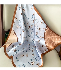 Detail of floral silk scarf with light blue print and contrasting brown satin border