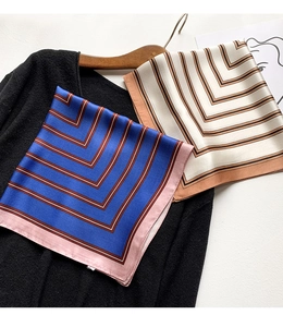 Detail of silk square scarves with geometric V-stripes displayed on a black knit sweater