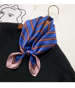 Close-up of a blue striped silk scarf knotted on a black sweater for an elegant office look