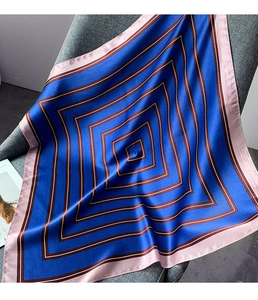 Close-up of royal blue silk scarf with geometric stripe patterns on grey fabric chair