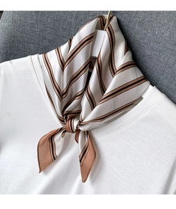 Close-up of silk scarf with brown and black stripes tied on a white shirt