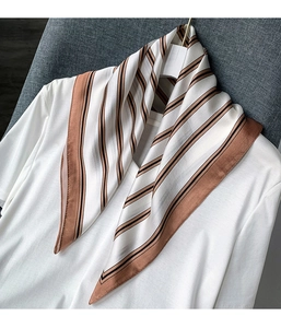 Close-up of elegant striped silk scarf draped on a white shirt with natural sheen