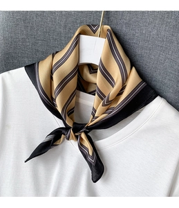 Close-up of a striped silk scarf tied in a bow on a white shirt for elegant styling