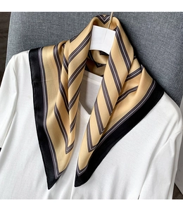 Detailed texture of a mulberry silk scarf with classic black and gold geometric stripes