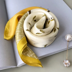 Floral print silk scarf in ginger yellow and beige on magazine with pearl pin accessory