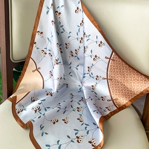 Light blue floral silk scarf with brown geometric borders draped on a chair