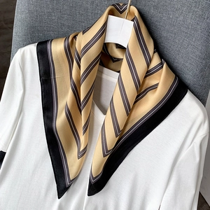 Champagne silk scarf with classic geometric stripes hanging on a white V-neck shirt