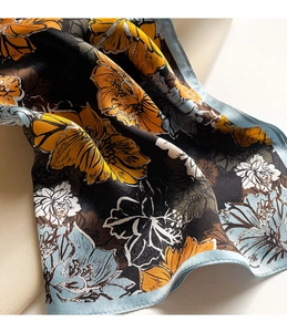 Makroaufnahme eines Seidenschals mit Blumenmuster und blauem Rollsaum-Detail
