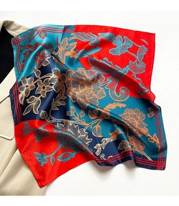 Detail eines Seidenschals mit Blumenprint und geometrischem Muster auf beigem Blazer