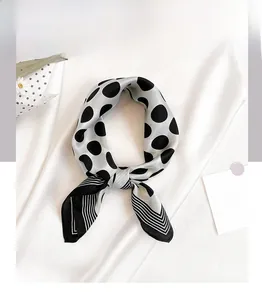 Detailed close-up of a silk scarf with black polka dots and striped pattern on silk background
