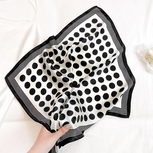 Detail shot of silk-like square scarf with black and white polka dots and striped border