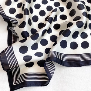 Detailed view of silk scarf with classic black polka dots and striped satin edges