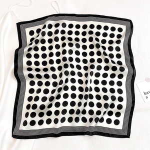 Detailed view of square silk scarf with classic black polka dots and border