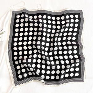 Detailed view of elegant black silk scarf with white polka dots and striped borders