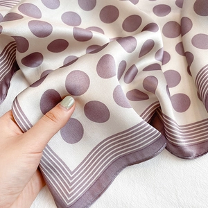 Macro view of silky polka dot scarf with striped borders and elegant satin sheen
